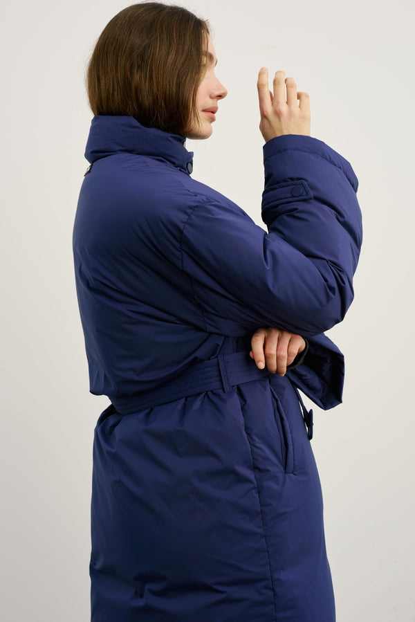 A model showcases a stylish navy blue MEOTINE puffer coat with a belted waist, highlighting its modern design and comfort.