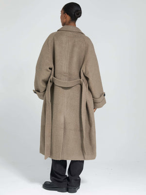 A model wearing a cozy, oversized brown coat with a belt, showcasing a relaxed fit and stylish design by MEOTINE.