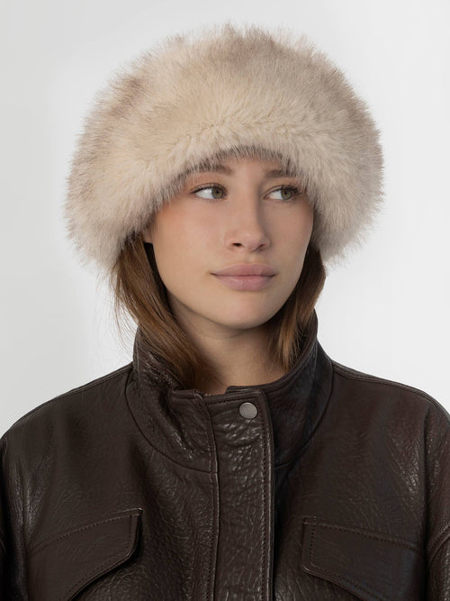 A model wearing a soft, fluffy beige hat paired with a dark brown leather jacket, showcasing MEOTINE's stylish winter accessory.