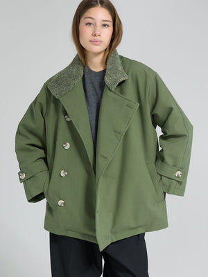 Oversized green coat with a soft, textured collar, styled casually over a dark shirt, showcasing MEOTINE's unique design.