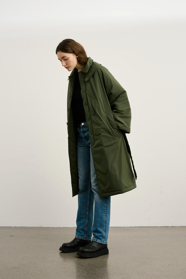 A model wearing a long olive green coat over a black top and blue jeans, showcasing MEOTINE's stylish outerwear.