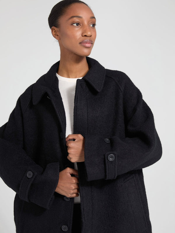 A model showcases a stylish black oversized coat from MEOTINE, featuring a button-up front and a relaxed fit, perfect for layering.