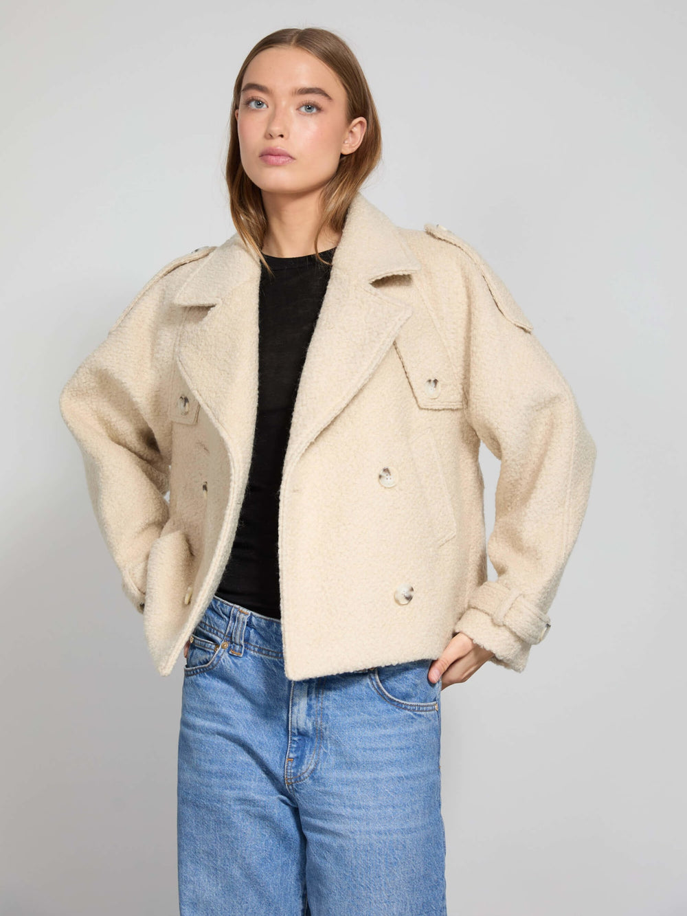 A model showcases a stylish cream-colored MEOTINE jacket with a relaxed fit, paired with blue jeans for a chic look.