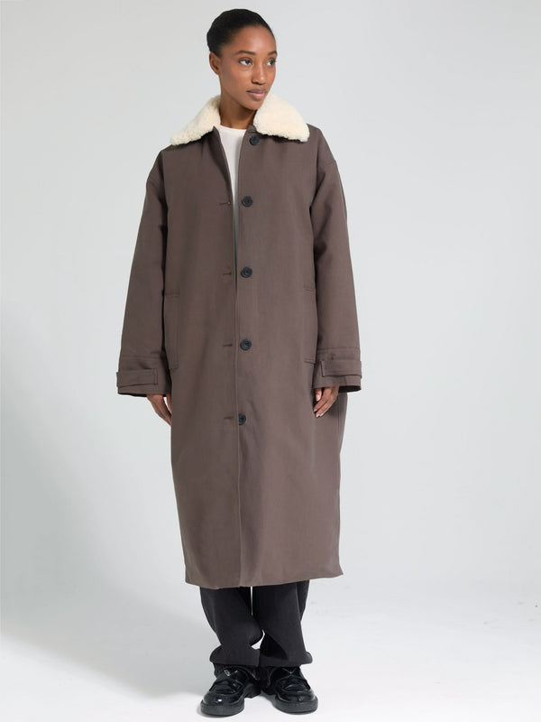 A model wearing a long brown coat with a white fur collar, showcasing MEOTINE's stylish and cozy outerwear design.