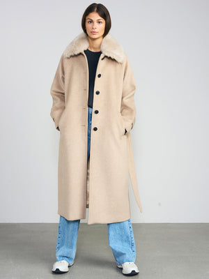 A model wearing a beige coat with a fur collar, paired with blue jeans and sneakers, showcasing MEOTINE's stylish outerwear.
