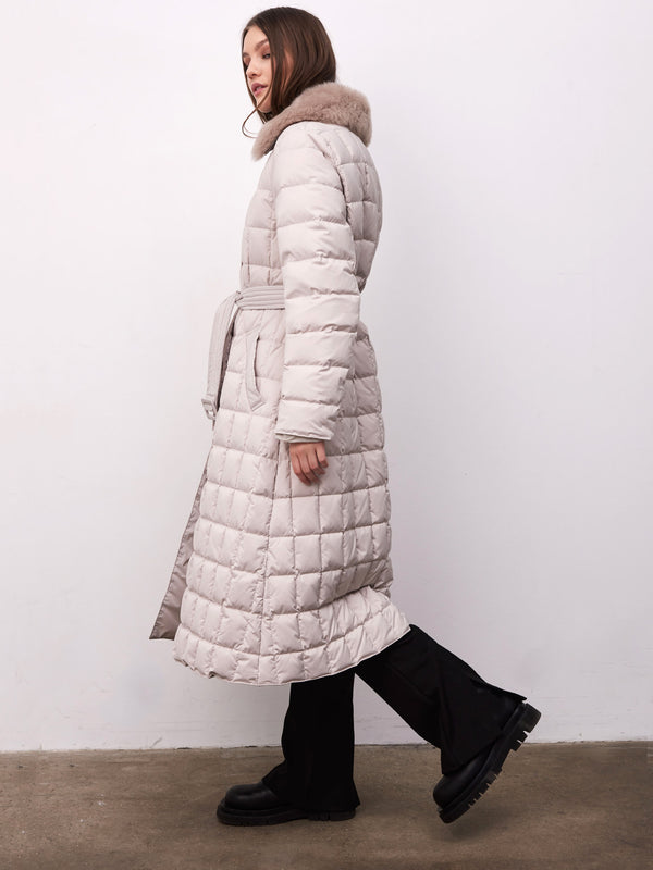 A model showcases a stylish MEOTINE long puffer coat with a fur-lined hood, paired with black pants and chunky boots.